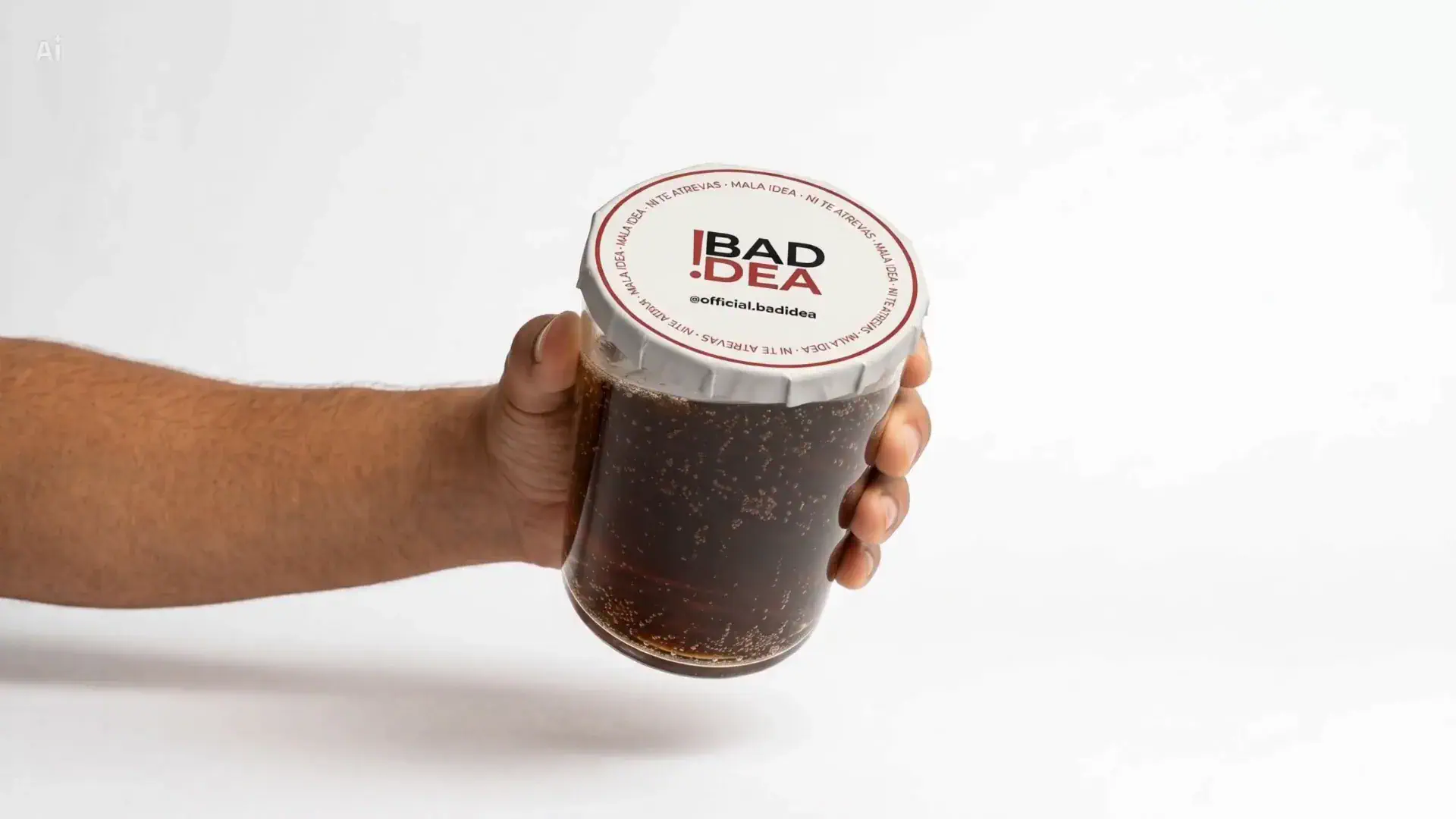 Vaso de refresco sujeto con la mano, cerrado por arriba con la tapa adhesiva BadIdea